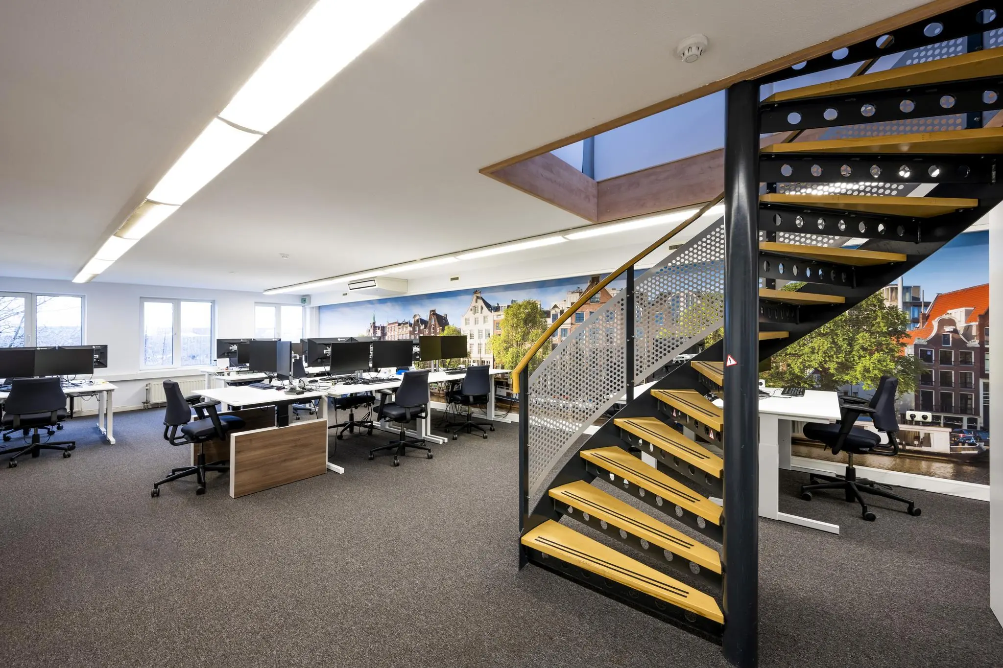 Modern kantoorinterieur aan de Prins Hendrikkade met open werkplekken en een metalen trap.